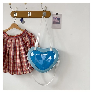 Blue heart-shaped Itabag with transparent window hanging on a hook with a plaid skirt