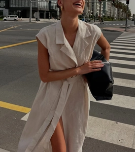 Detail of beige sleeveless linen midi dress with lapel collar and waist tie belt