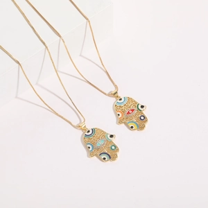 Detail view of Hamsa Hand pendants with colorful enamel eyes and rhinestones on a white stand