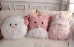 Close-up of plush Christmas pillows with snowman, reindeer and gnome designs on a sofa