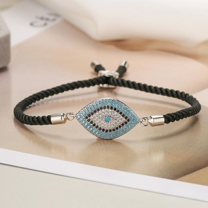 Detailed macro shot of the blue and white zircon evil eye charm on black woven bracelet
