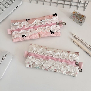 Detailed view of quilted lace pencil cases with silver flower zippers on a white desk