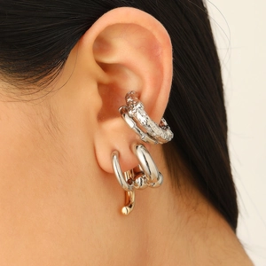 Macro shot of silver lava textured ear cuffs and polished rings for stacked styling