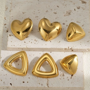 Polished 18k gold heart and triangle earrings displayed on natural travertine stone base