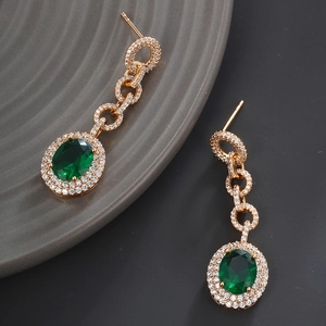 Macro shot of tiered emerald drop earrings featuring full diamond accents and gold plating