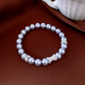 Vue détaillée du bracelet de perles avec breloque nœud en cristal sur tissu sombre