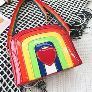Detail of rainbow crossbody bag with red heart patch on a black and white grid