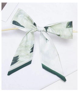 Detail of green floral satin ribbon tied in a bow with elegant silk texture