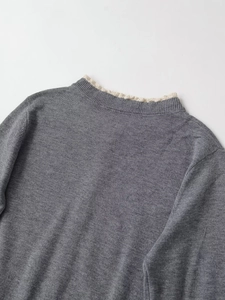 Close-up of grey knit sweater featuring delicate cream lace trim at the round neckline