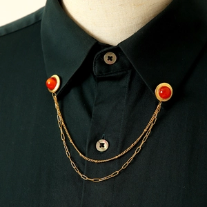 Dettaglio di catene per colletto vintage dorate con strass rossi su camicia nera