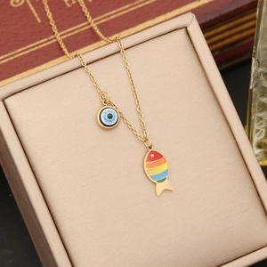 Gold chain necklace with colorful fish pendant and evil eye charm on a jewelry box