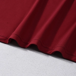 Detailed macro shot of burgundy red ruched dress fabric with premium reinforced stitching