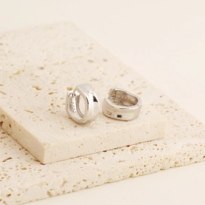 Detailed close-up of chunky S925 sterling silver hoop earrings on a stone display