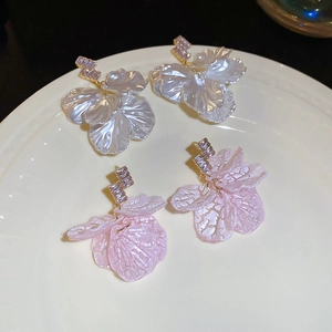 Close-up of shell petal earrings with zirconia accents on a ceramic plate