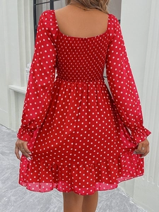 Detail view of red polka dot dress featuring ruched back design and ruffled hemline