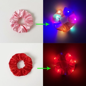 Detail view of pink and red LED scrunchies glowing in dark with satin texture finish