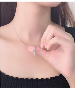 Close-up of minimalist silver cross necklace showing refined pendant texture on neck