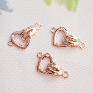 Macro detail of three rose gold heart shaped jewelry connectors for DIY necklaces