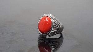 Macro shot of vintage titanium steel ring with a large red oval stone and carved textures