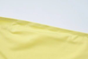 Dettaglio del tessuto giallo con cuciture precise e trama morbida del vestito lungo