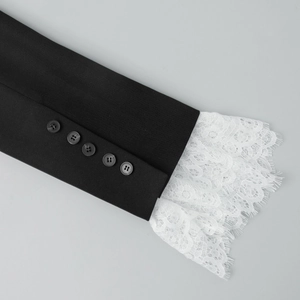 Detailed view of black blazer sleeve with white lace trim and five decorative buttons