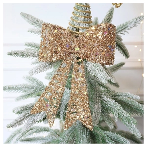 Close-up of golden glitter Christmas tree topper bow with sparkling star sequins