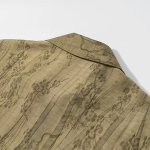Macro view of moss green jacquard fabric with dark floral print and pleated texture