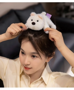 Close-up of a white plush bear hair accessory worn by a model in a warm home setting