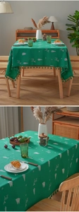 Detail of green Christmas tablecloth featuring white reindeer embroidery and festive tassels