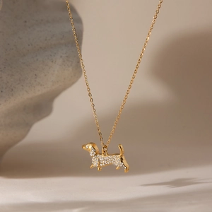 Golden dachshund pendant necklace with sparkling pavé crystals on elegant stone surface