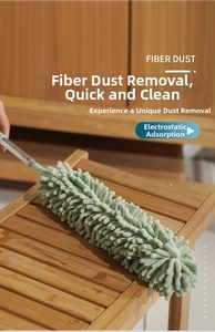 Green microfiber chenille duster with telescopic handle on wooden furniture surface