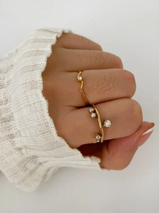Close-up of gold plated crisscross and wavy zircon rings worn on a hand