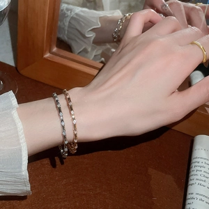 Detailed view of silver and gold bamboo style bracelets with micro zircons on a model
