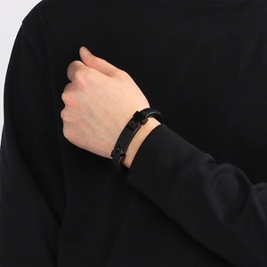 Close-up of a minimalist black braided leather bracelet with a black matte metal clasp