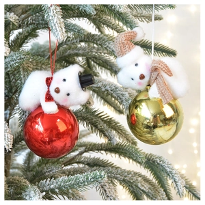 Close-up of cute plush bears on red and gold ornaments hanging on a snowy Christmas tree