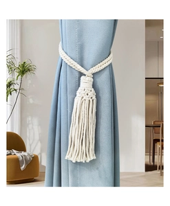 Detail of cream cotton rope curtain tieback with handcrafted tassel in bohemian style