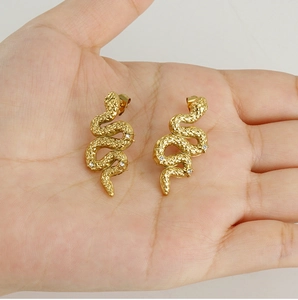 Detailed view of 18K gold plated snake stud earrings with zircons held in hand
