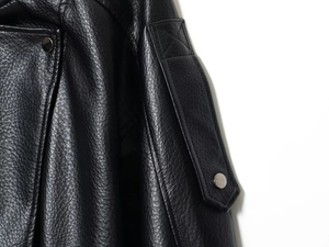 Detail of black leather jacket shoulder with decorative epaulet, snap button and stitching