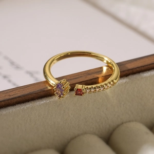 Detail of gold-plated open ring featuring red and purple stones with side pavé zircons