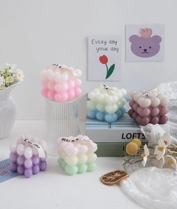 Artistic arrangement of gradient cube candles with ribbons and decorative dried flowers
