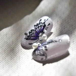 Macro detail of butterfly nail stickers with pearls and rhinestones on gradient base