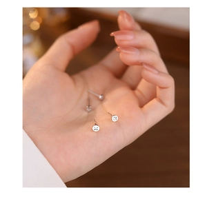 Detailed close-up of two pairs of mini s925 silver cross stud earrings held in hand