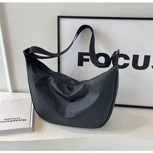 Detail of black nylon dumpling crossbody bag with adjustable wide strap on white background