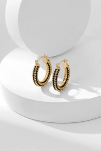 Detailed view of golden hoop earrings featuring triple-row micro-pave black beads
