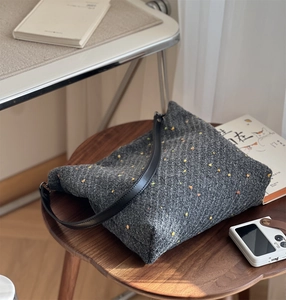 Detail of gray tweed tote bag with color specks and premium black leather shoulder strap