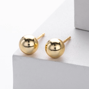 Macro shot of polished gold ball earrings showing S925 hallmark on a white background