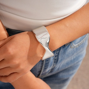Close-up of polished silver irregular geometric open cuff bracelet on female wrist