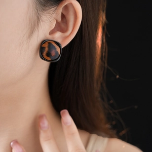 Gros plan de boucles d'oreilles carrées motif léopard portées par un mannequin