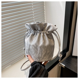 Close-up of silver bucket bag with pleated metallic texture and drawstring closure