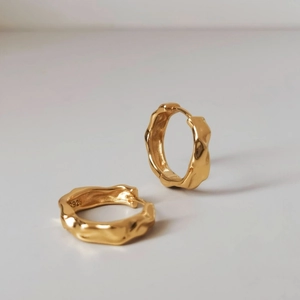 Macro detail of gold S925 silver hoop earring with irregular lava texture finish